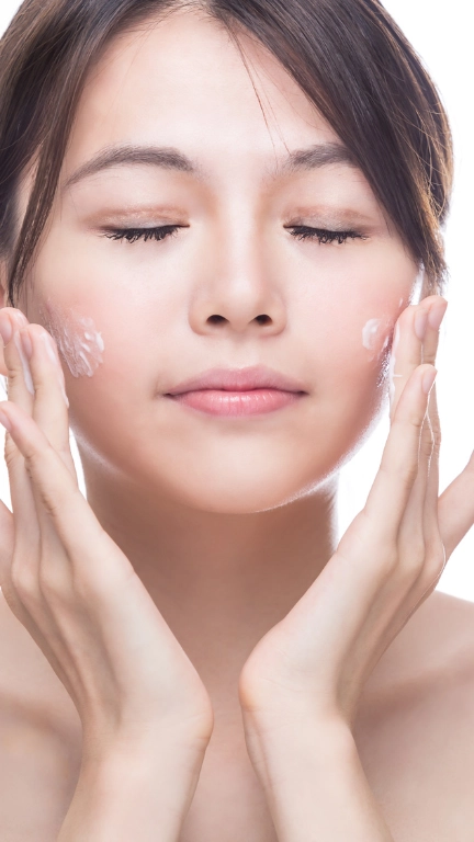 East Asian woman applying skincare to her face