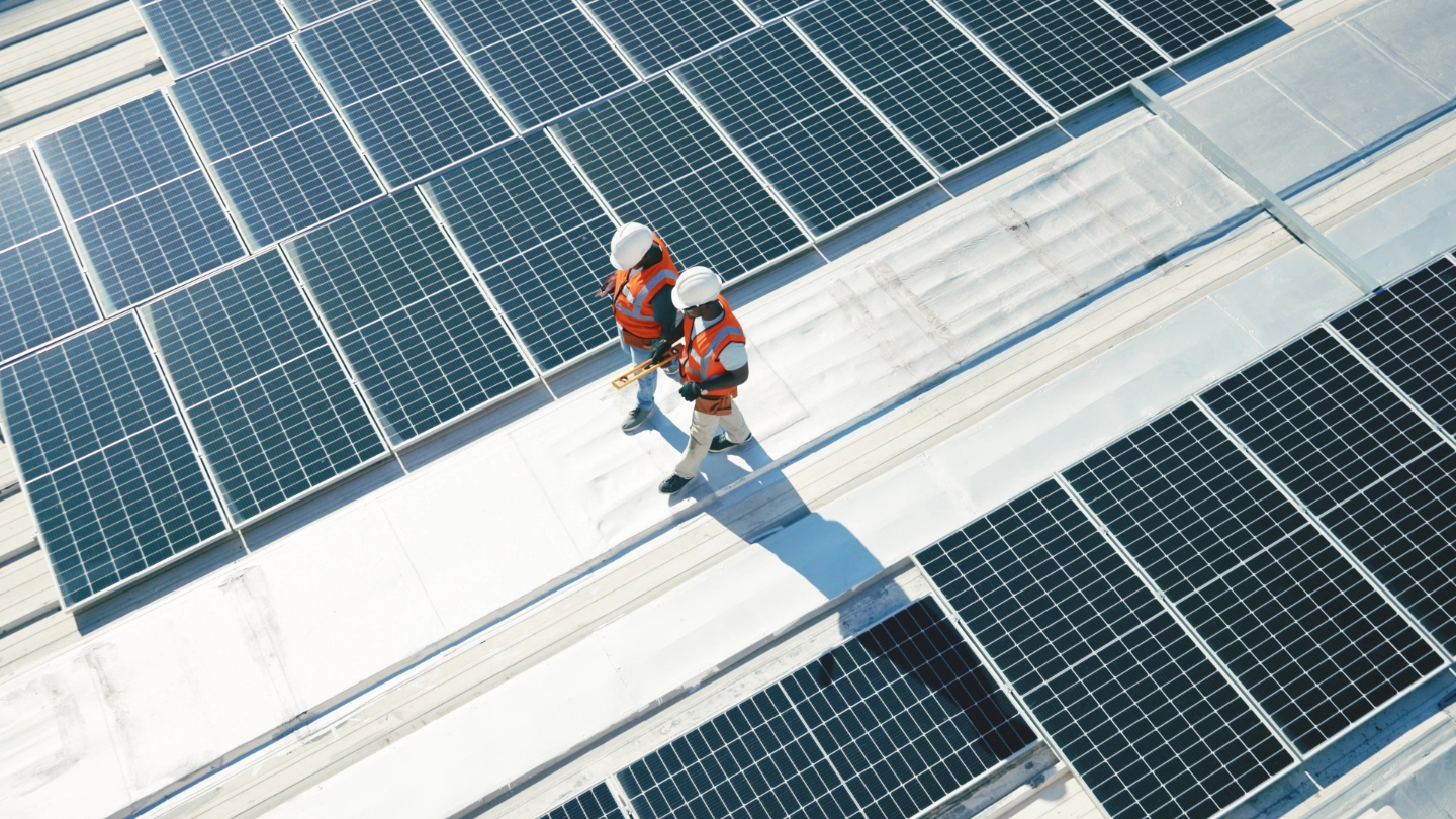 Two solar panel workers walking alongside panels Two solar panel workers walking alongside panels