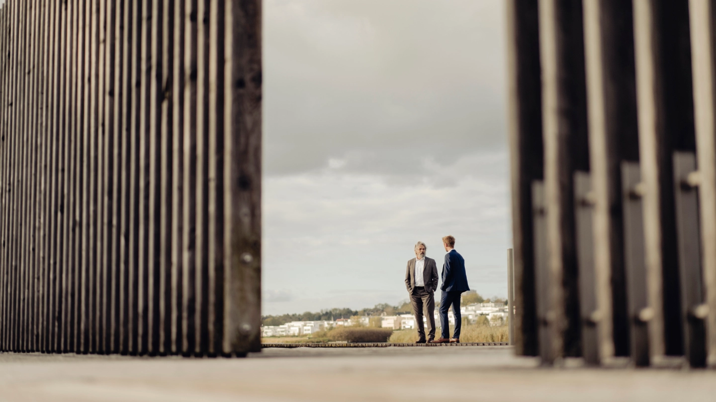 Two businessmen standing behind fencing