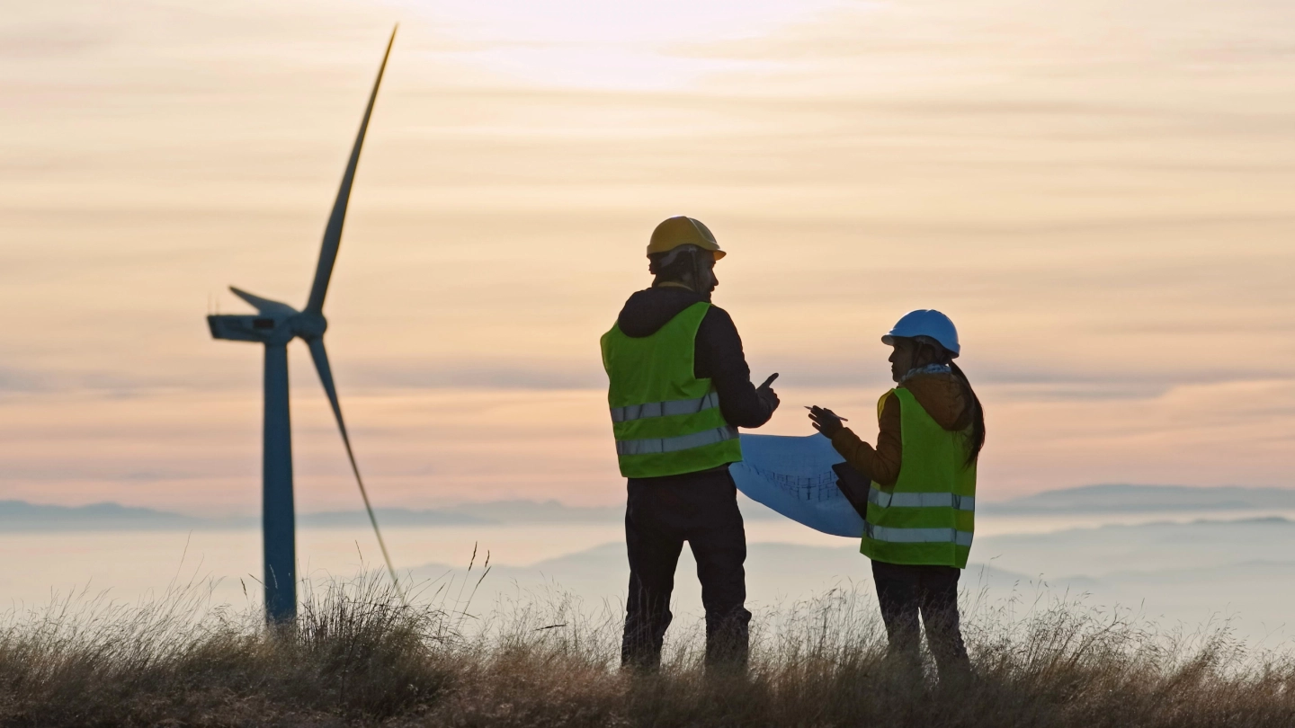 Two wind turbine engineers at sunset (FLIPPED) Two wind turbine engineers at sunset