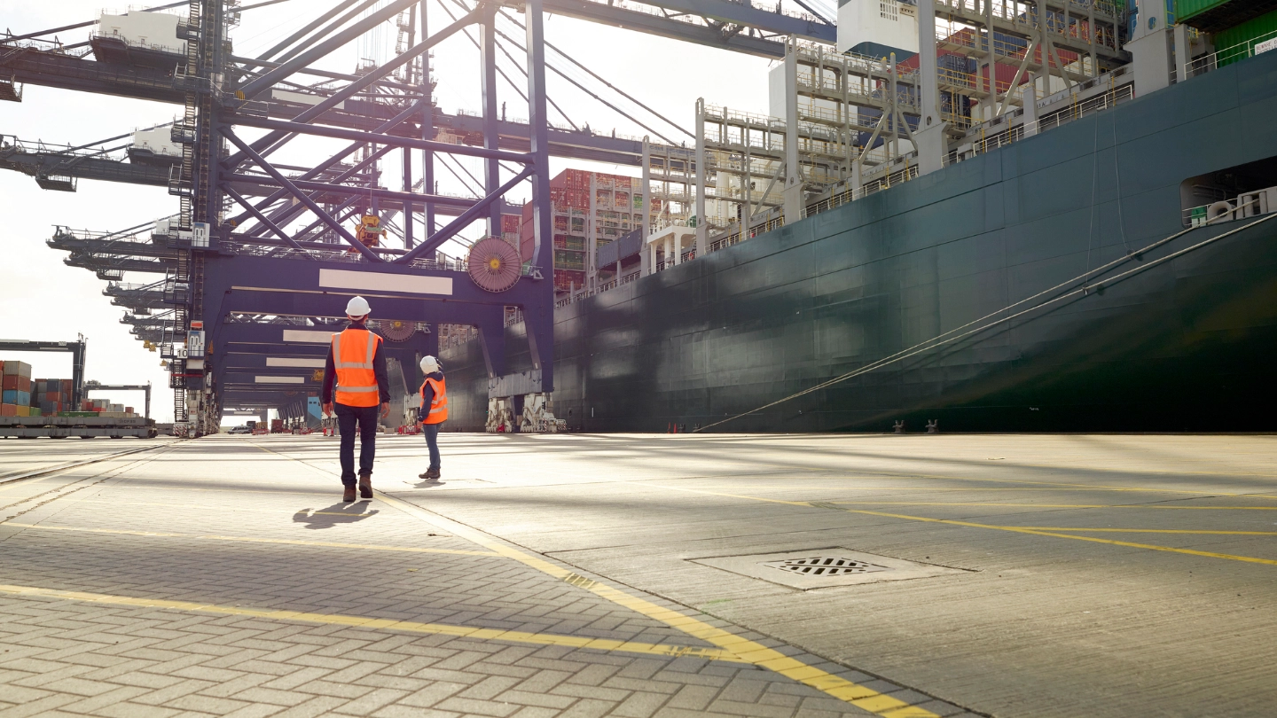 Dock workers beside cargo ship at Port of Felixstowe, England Dock workers beside cargo ship at Port of Felixstowe, England